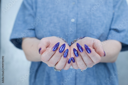 Female hand with long nails and a blue and purple color nail polish photo