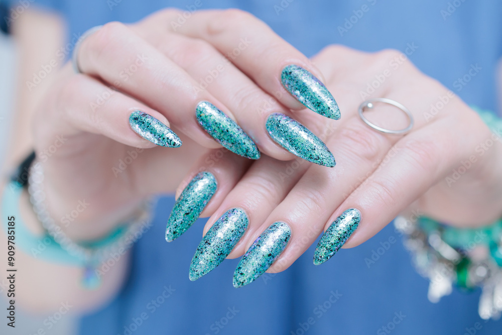 Female hand with long nails and light turquoise manicure, blue and green color Female hand with long nails and light turquoise manicure, blue and green color