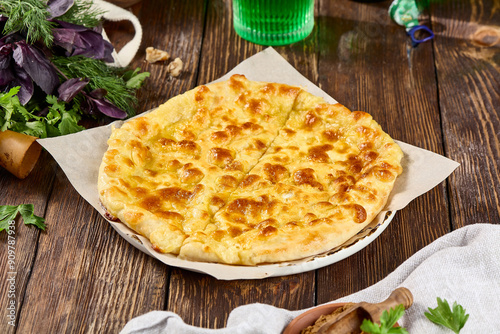 Georgian Megrelian Khachapuri on Rustic Table with Herbs and Parsley photo