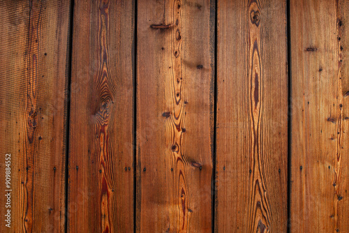 Old brown wooden wall made of knotted planks arranged vertically