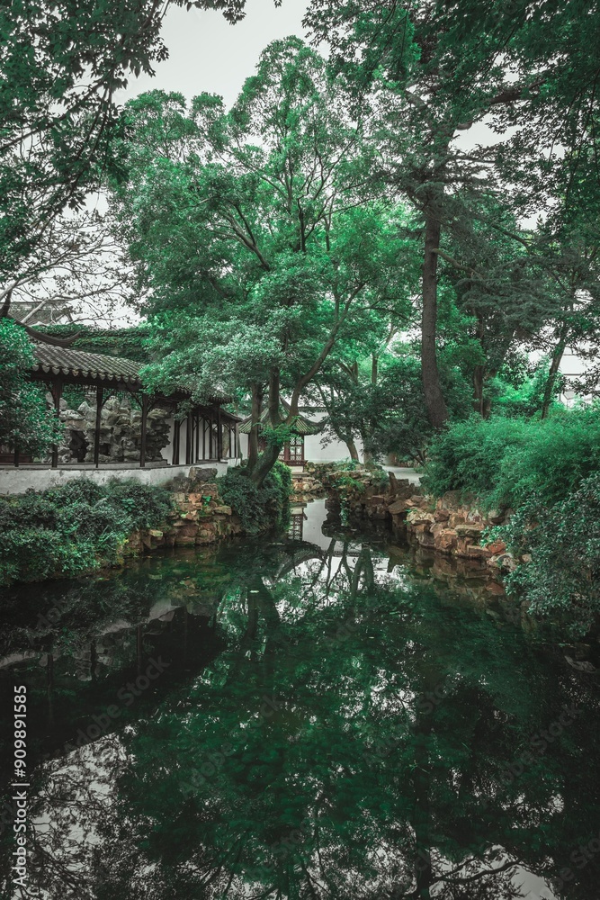 A tranquil pond in a Chinese garden, reflecting the surrounding trees and foliage. A tranquil pond in a Chinese garden, reflecting the surrounding trees and foliage.