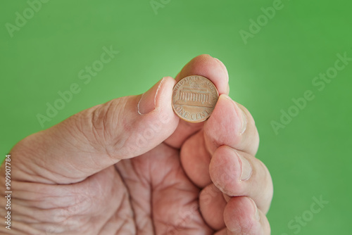 One cent coin in hand on a green background close-up, one cent in hand, minimum bet, minimum payment