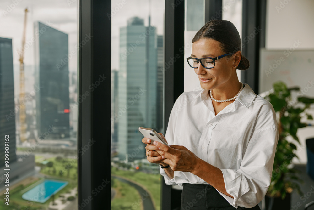 Fototapeta premium A Business Professional uses a Smartphone in a Modern Office to enhance productivity