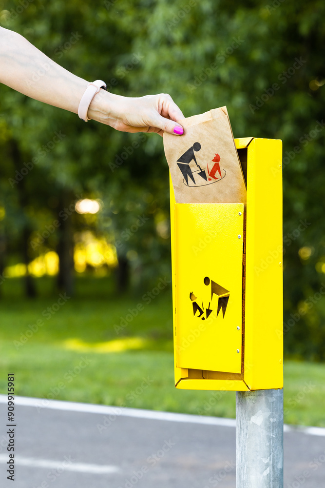 Photos hand takes out a paper bag for dog excrement from a box in the park