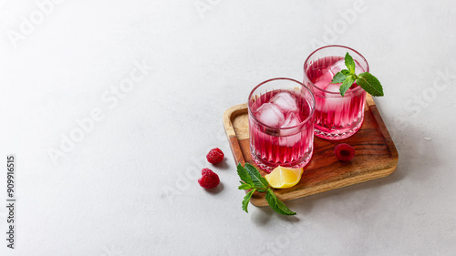 Raspberry cocktail with ice in a glass on a light background