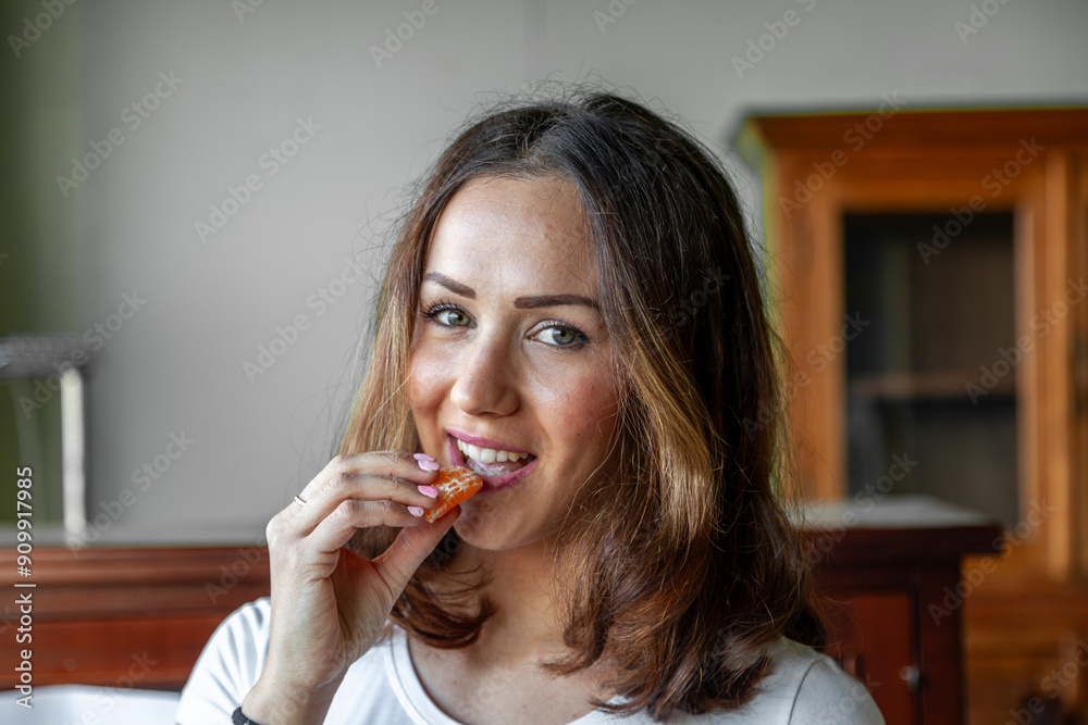 portrait of young beautiful woman is eating an orange in her house portrait of young beautiful woman is eating an orange in her house