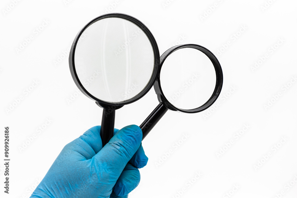 Mano con guante azul sosteniendo dos lupas a modo de búsqueda, aislado en blanco Mano con guante azul sosteniendo dos lupas a modo de búsqueda, aislado en blanco