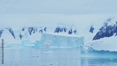 Iceberg Floating in Ocean on Sea with Antarctica Mountains on Antarctic Peninsula Coast, Beautiful Dramatic Blue Coastal Landscape and Seascape in Icy Winter Sea Scene with Ice