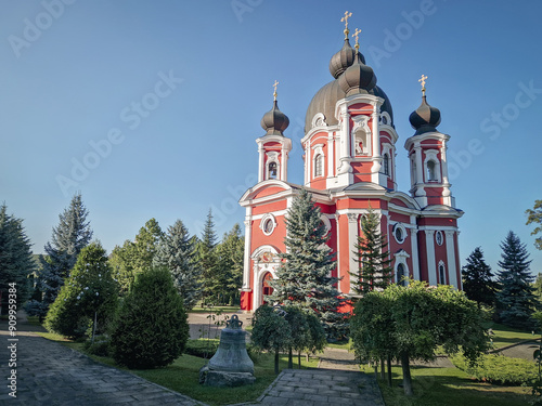 Curchi Monastery outdoor view. Christian Orthodox style church traditional for eastern Europe culture located in Orhei, Moldova. Beautiful garden with trees around the basilica and the big bell