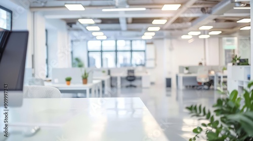 Modern office interior with white desks  chairs  and plants  with a large window and a computer screen in the foreground.