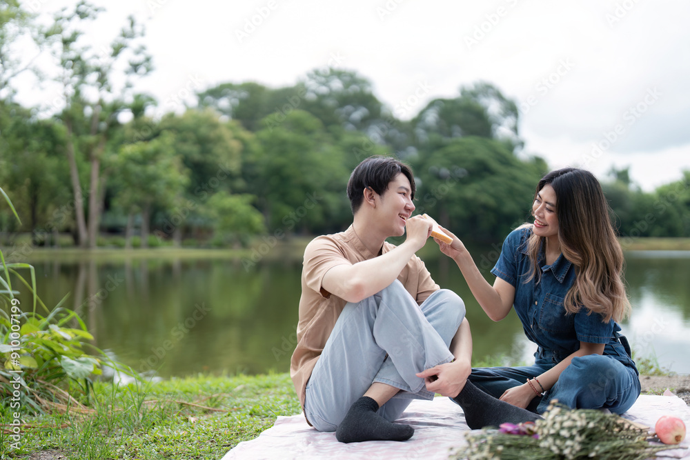 Romantic Couple Enjoying a Picnic by the Lake in a Serene Park Setting with Lush Greenery and Tranquil Waters Romantic Couple Enjoying a Picnic by the Lake in a Serene Park Setting with Lush Greenery and Tranquil Waters