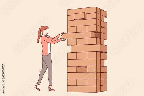 Woman plays jenga game, pulling blocks from giant tower, to develop skills of equilibrium and balance that allow to succeed. Jenga game for entertainment and fun free time with friends or alone