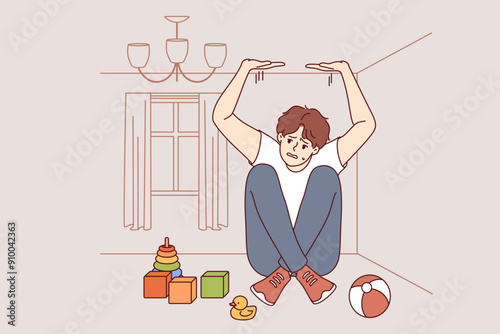 Boy suffers from claustrophobia, feeling pressure of walls and sitting in small room with scattered toys. Problem of claustrophobia in person with panic attack associated with negative memories