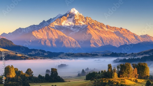 Stunning Snow-Capped Mountain Peaks Bathed in Golden Sunrise Light, Illuminated Summit with Clear Sky and Tranquil Valley Shrouded in Morning Mist