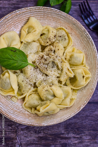 Home made vegetarian italian Tortellini with pesto genovese filled with spinach and parmesan cheese, decorated with fresh basil