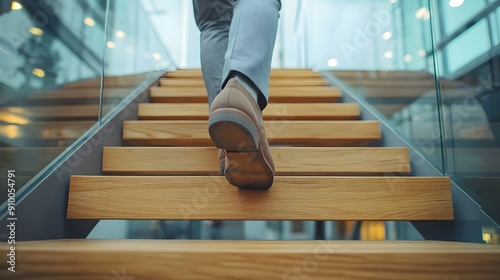 Modern staircase, glass and metal architecture, close-up of feet walking up wooden steps, business shoes, grey trousers, dynamic movement, low angle view, shallow depth of field.