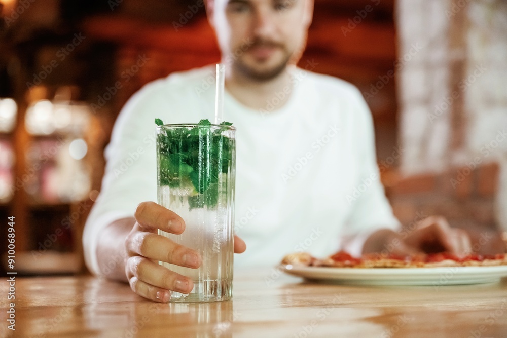 With mojito. Man is sitting in the restaurant and eating a pizza With mojito. Man is sitting in the restaurant and eating a pizza
