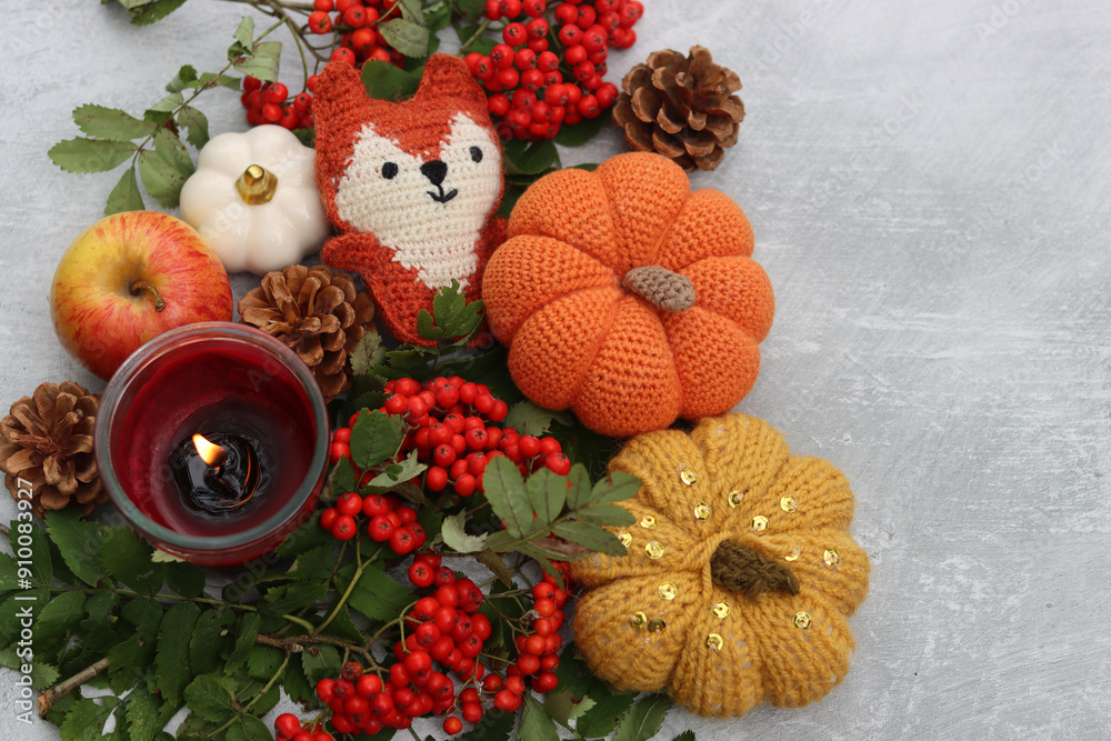 Handmade fox toy, pumpkins, apples, rowan berries and a candle on a light background with space for text. Autumn decorations close up photo. Handmade fox toy, pumpkins, apples, rowan berries and a candle on a light background with space for text. Autumn decorations close up photo.