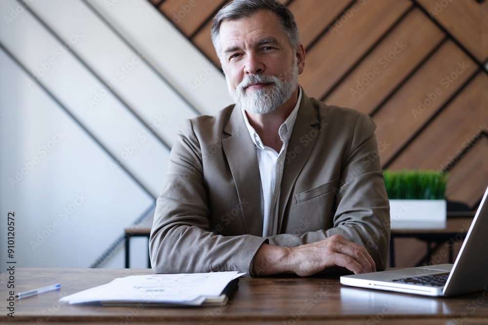 Naklejka premium Smiling mature business man executive wearing shirt sitting at desk using laptop. Happy busy professional middle aged manager investor working on computer in office