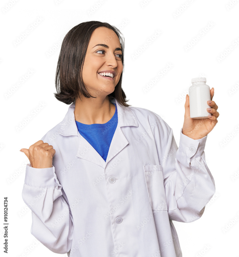 Young Caucasian female pharmacist with pills points with thumb finger away, laughing and carefree. Young Caucasian female pharmacist with pills points with thumb finger away, laughing and carefree.