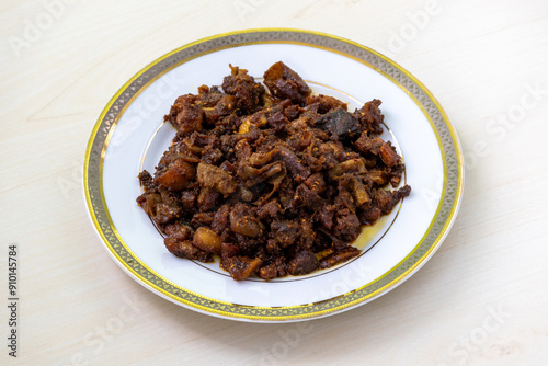 Gorur bot bhaja or gorur vuri bhuna in a white plate on wooden background. Beef Bhuri Vaja is a popular Bengali dish made from beef tripe. photo