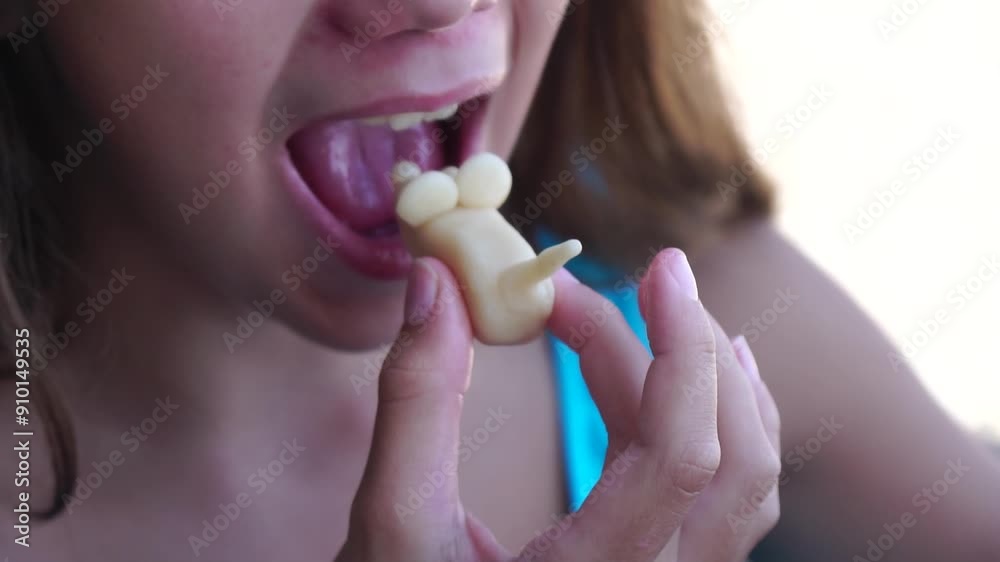 Close-up of a Girl Eating a Unicorn Shaped Candy