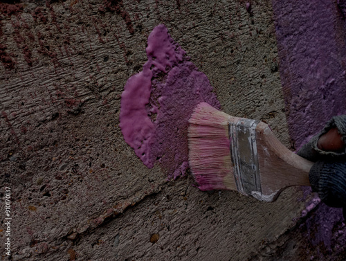 The process of priming a concrete wall with pink concrete contact manually using a brush.