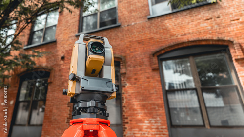 land surveying total station instrument on a tripod with a building in the background