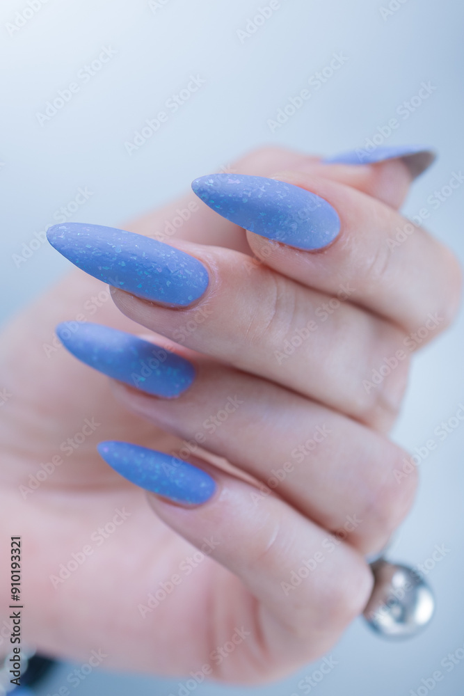 Woman's beautiful hand with long nails and light baby blue manicure	