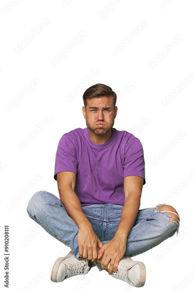 Casual man sitting on floor blows cheeks, has tired expression. Facial expression concept. Casual man sitting on floor blows cheeks, has tired expression. Facial expression concept.