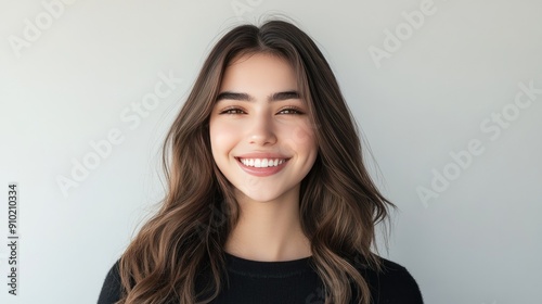 Head and shoulders portrait of a young woman with a charismatic smile and long brown hair, showcasing her charm on a white background