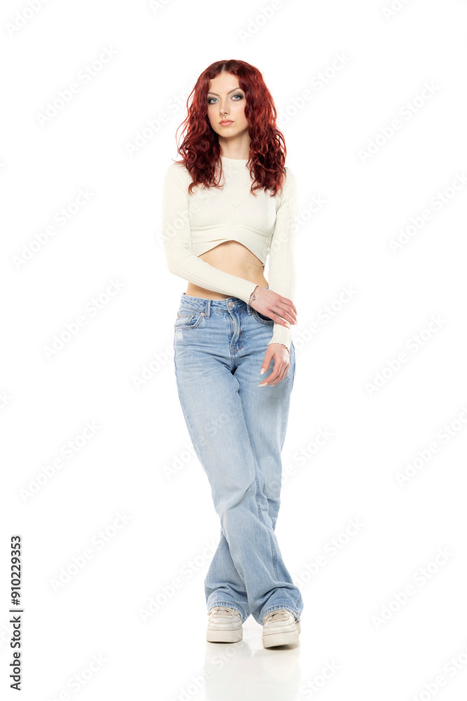 Charming young redhead woman posing in studio in white short blouse and blue jeans. Charming young redhead woman posing in studio in white short blouse and blue jeans.