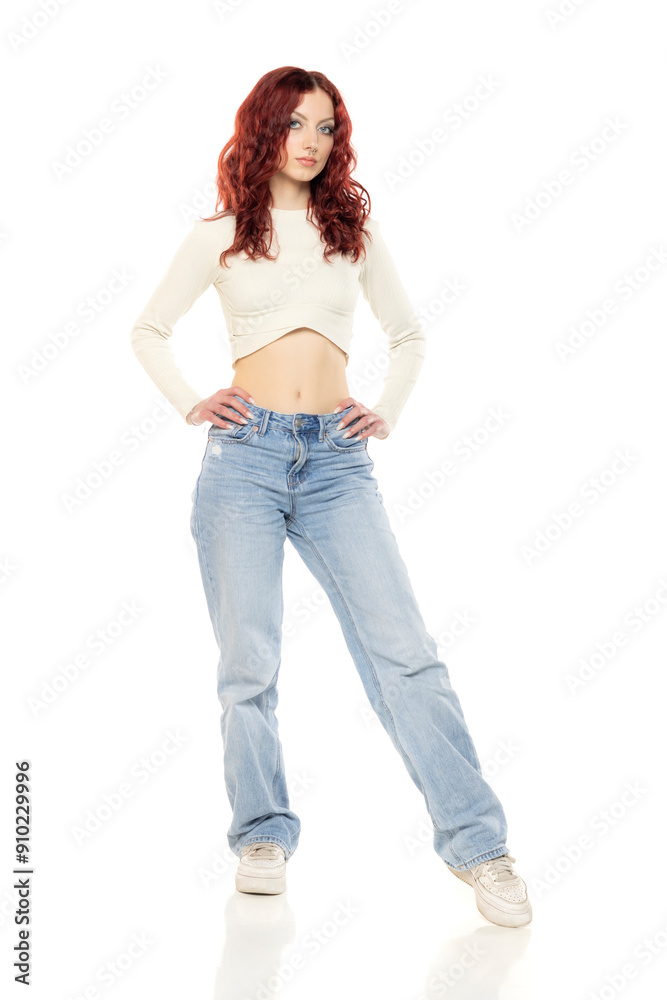 Charming young redhead woman posing in studio in white short blouse and blue jeans. Charming young redhead woman posing in studio in white short blouse and blue jeans.