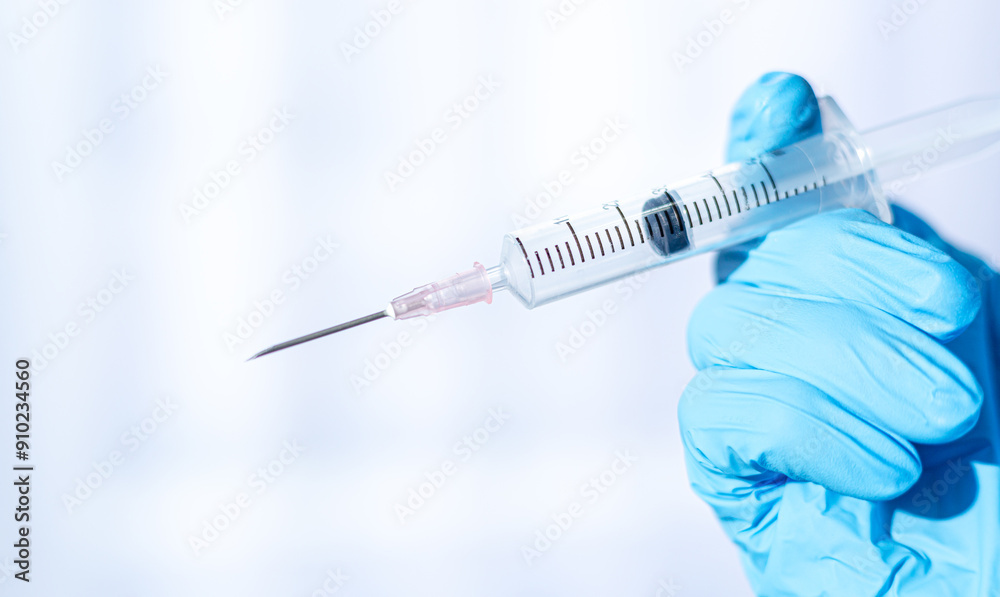 Human hand wearing medical gloves holds a syringe needle,Doctor hands with syringe on light background Human hand wearing medical gloves holds a syringe needle,Doctor hands with syringe on light background