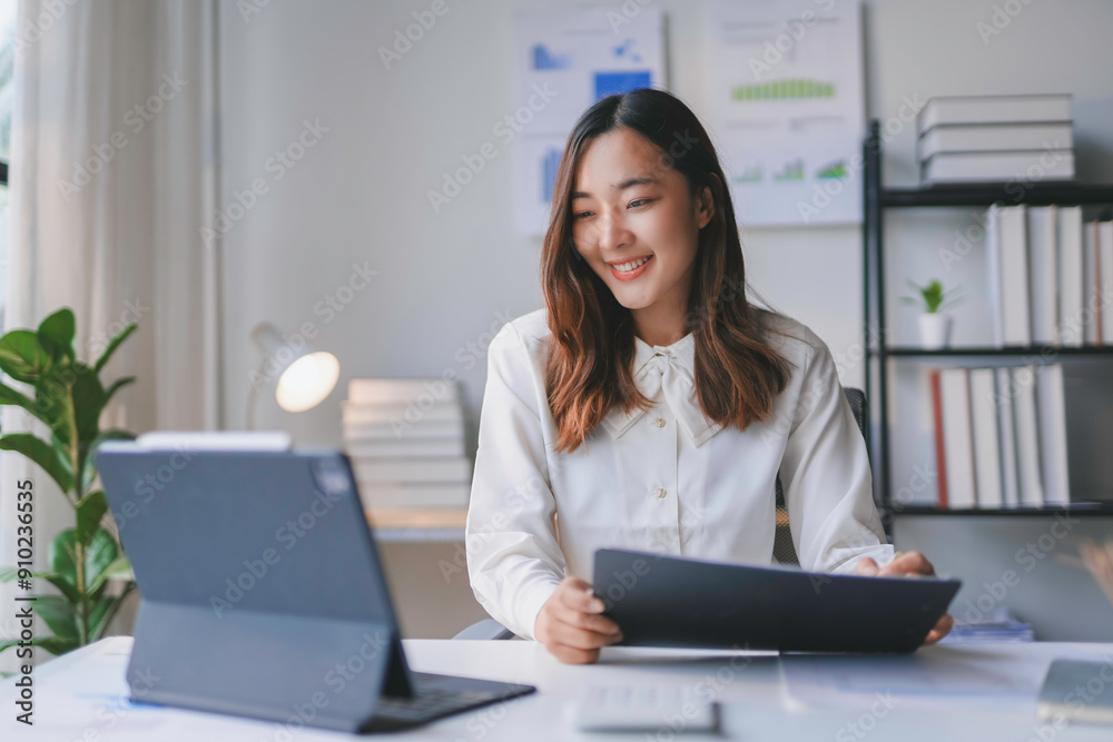 Asian businesswoman is smiling while working from her home office and using a tablet computer for a video conference call Asian businesswoman is smiling while working from her home office and using a tablet computer for a video conference call