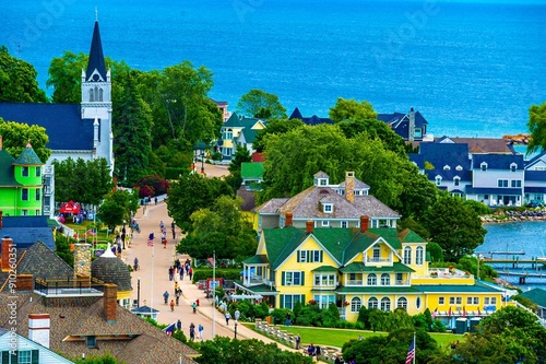 Scenic view of Mackinac Island with colorful houses, a church, and people walking along the street