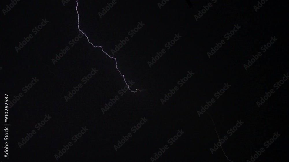 Flashes of lightning in the night sky among thunderclouds.
