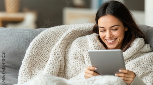 Happy woman reading a tablet on the sofa at home - Smiling girl enjoying day off lying on the couch - 