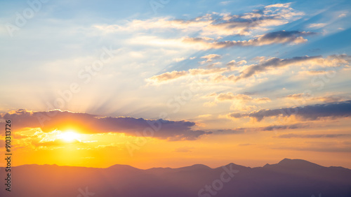 The setting sun over the mountains, the beautiful sun's rays shine through the clouds, the natural background, freedom, tranquility and peace