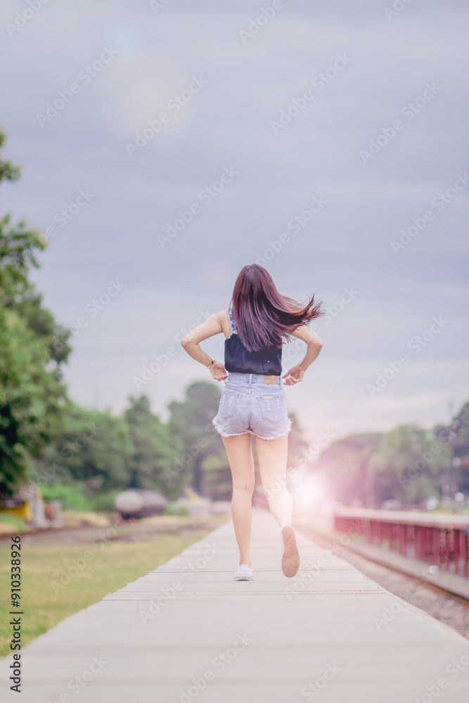 soft and Smooth Focus, A young Asian woman walks alone along the railroad tracks towards her desired destination. The back of a young woman walking alone on the train tracks in loneliness. soft and Smooth Focus, A young Asian woman walks alone along the railroad tracks towards her desired destination. The back of a young woman walking alone on the train tracks in loneliness.