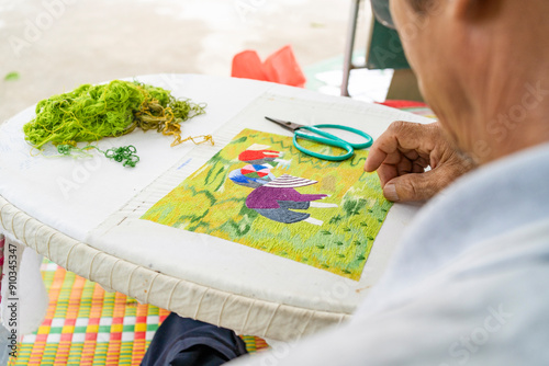 Traditional Vietnamese sewer at work with vibrant textile