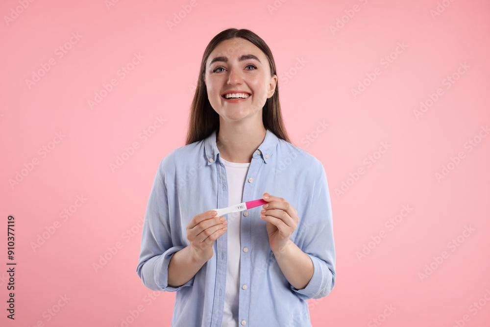 Happy woman holding pregnancy test on pink background Happy woman holding pregnancy test on pink background