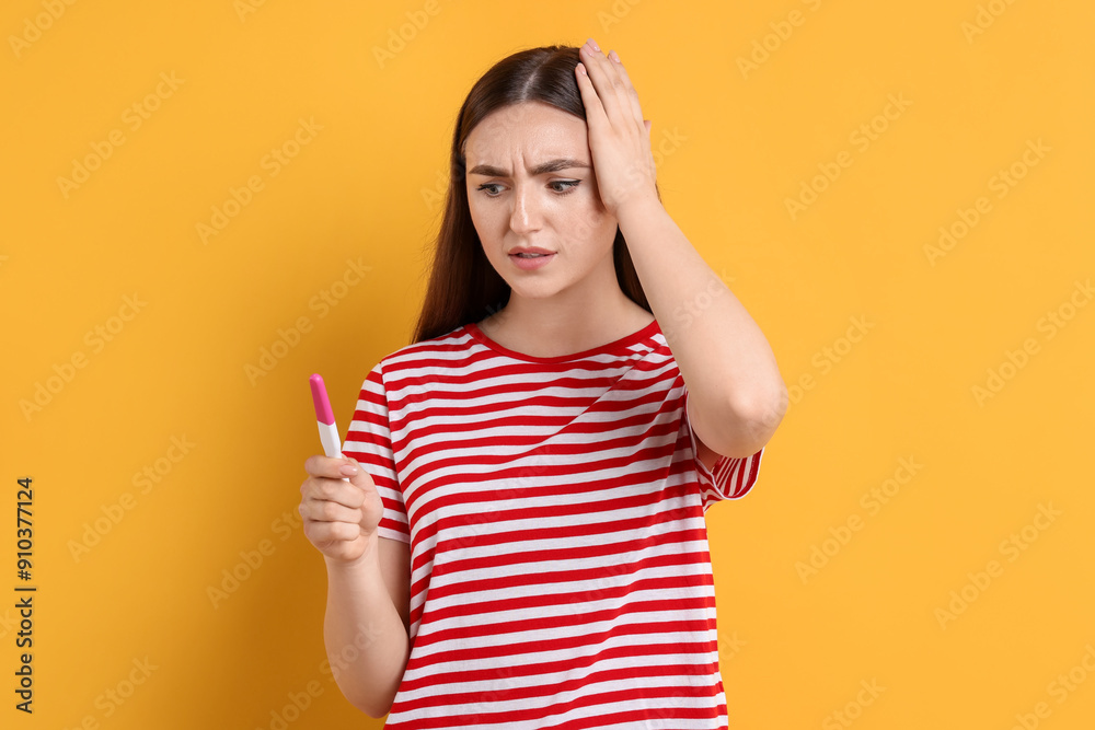 Confused woman holding pregnancy test on orange background Confused woman holding pregnancy test on orange background