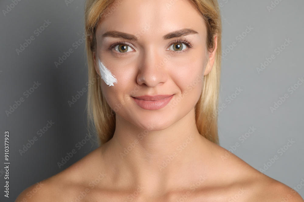 Beautiful woman with cream on her face against grey background, closeup Beautiful woman with cream on her face against grey background, closeup