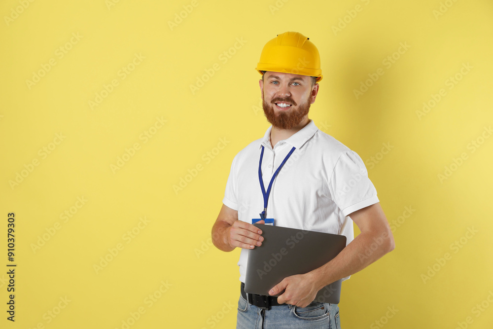 Engineer in hard hat with laptop on yellow background, space for text Engineer in hard hat with laptop on yellow background, space for text