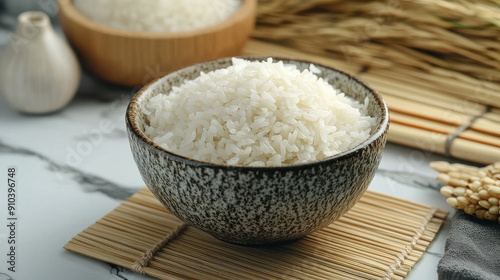 Close-up of a bowl filled with freshly cooked white rice, with selective focus emphasizing the soft, fluffy texture of the rice grains, set on a mat backdrop.