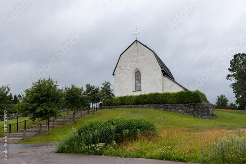 Tierp,Sweden - July 17 2024: Exterior of Tolfta white stone church in Swedish countryside. Stairs leading up to building in summertime. No visible people photo