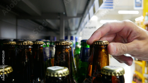 Close-up of a male buyer's hand choosing a glass beer bottle