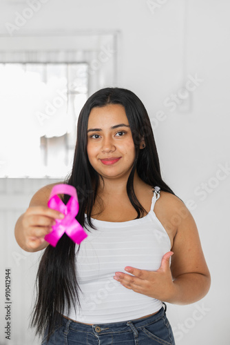 young latin brunette woman holding a pink ribbon in her hand while touching her breast with the other hand