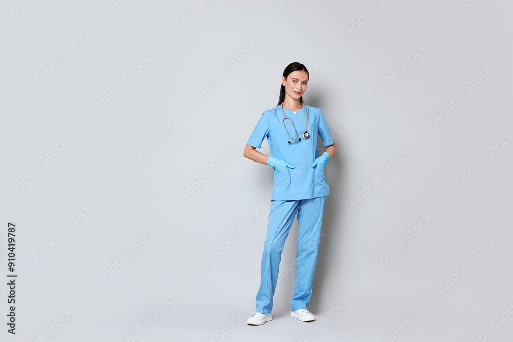 Beautiful nurse in uniform on grey background. Space for text Beautiful nurse in uniform on grey background. Space for text